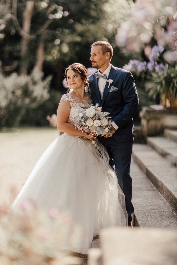 Hochzeitspaar traut sich im Barocken Stil in einem Gut. Beide schauen verliebt in die Kamera