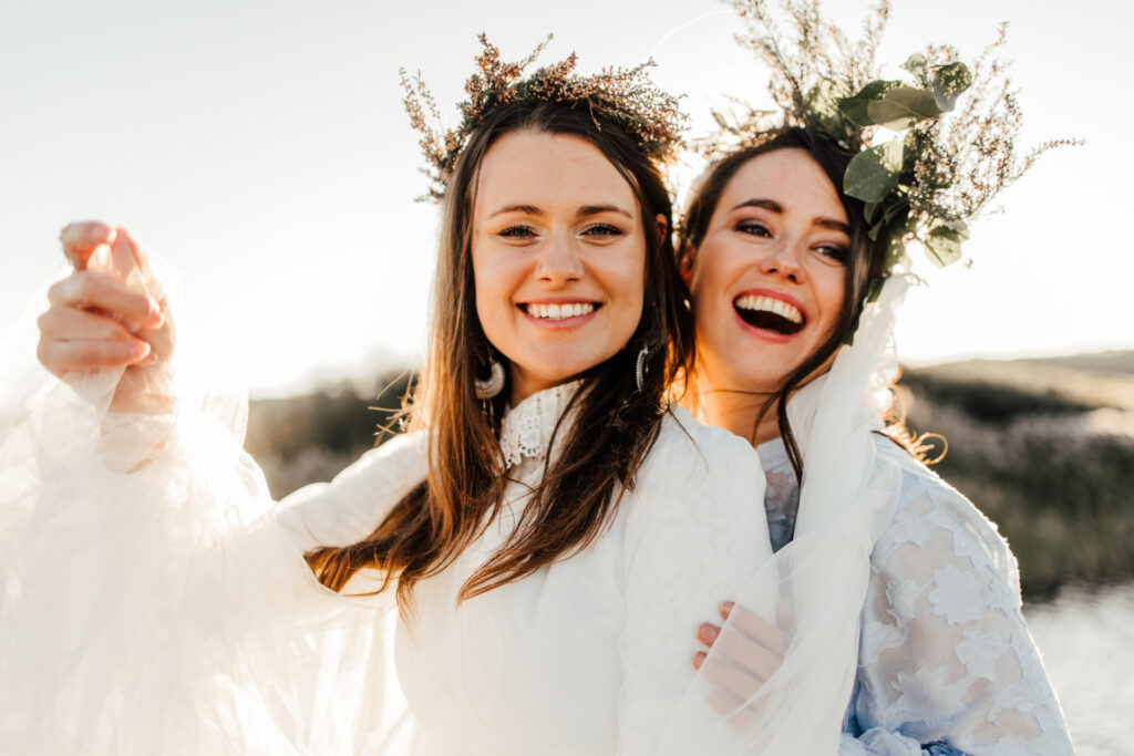 Zwei dunkelhaarige Bräute heiraten in der Landschaft von Hvide Sande bei untergehender Sonne