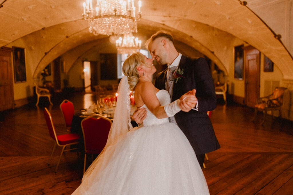 Hochzeitsfotografie und Hochzeitsvideografie - Schloss Glücksburg - Braut und Bräutigam schneiden die Torte im Schloss an