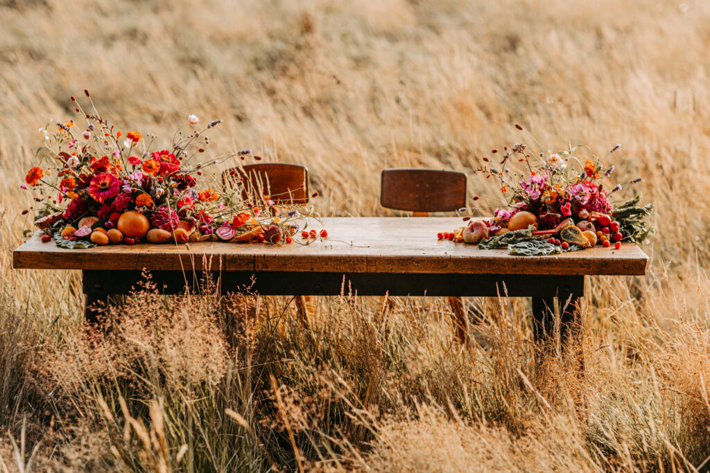 Ein Tisch mit zwei Stülen mitten auf dem Feld. Auf dem Tisch wunderschöne Blumendeko.