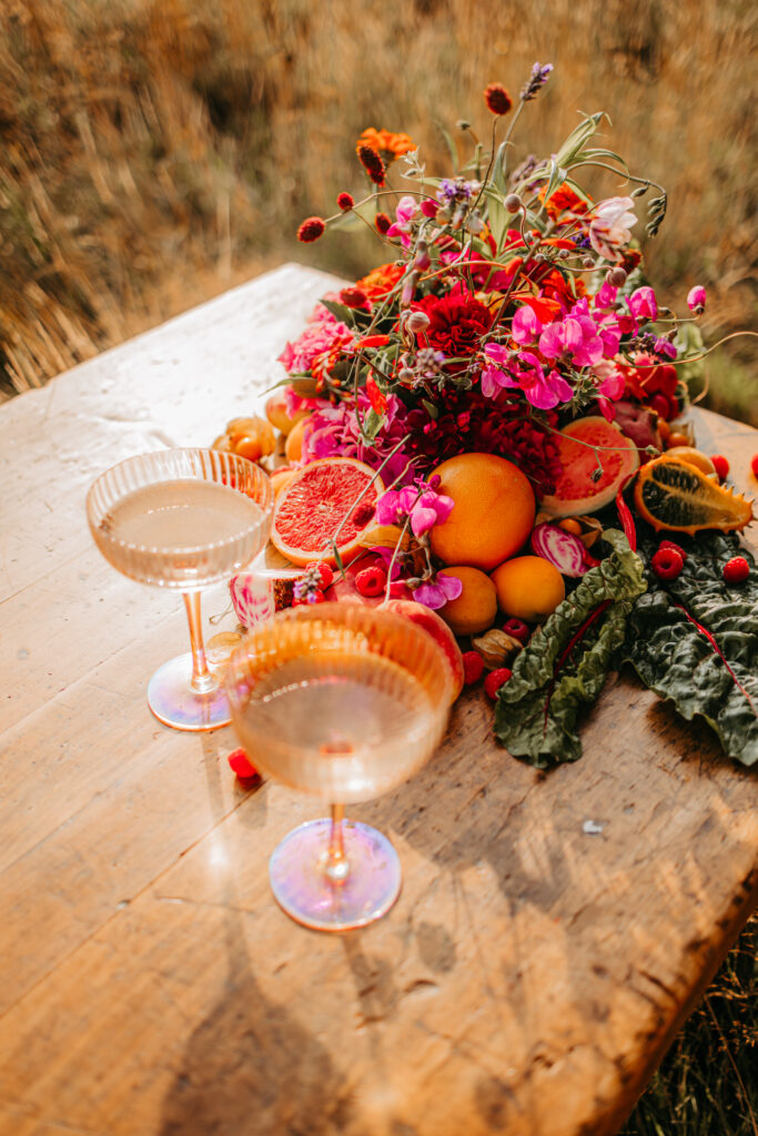 Zwei Weingläser zusammen auf dem Tisch mit rustikaler und bunter Blumendeko.