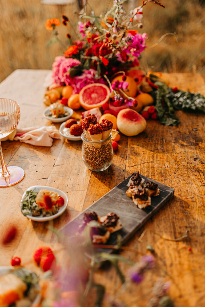 Ein bunter Tisch mit Blumen und kleinen Kuchen.