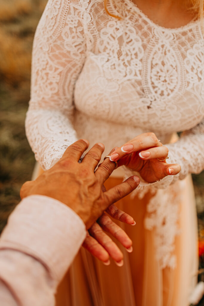 Die Braut steckt dem Bräutigam den Ring an den Finger.