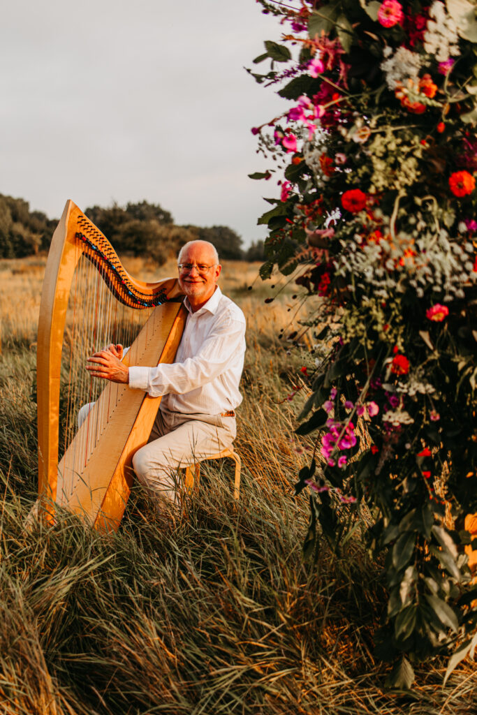 Ein Hochzeitsgast spielt Harfe auf der Blumenwiese.