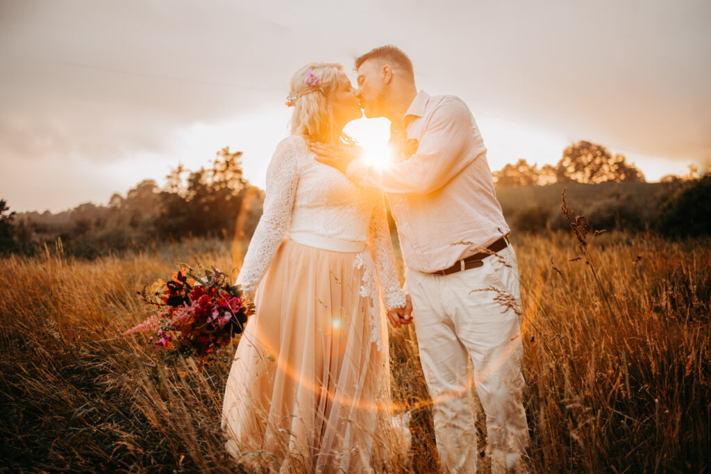 Eine besondere Hochzeit im Urlaub klingt aus. Das glückliche Ehepaar küsst sich im Sonnenuntergang.