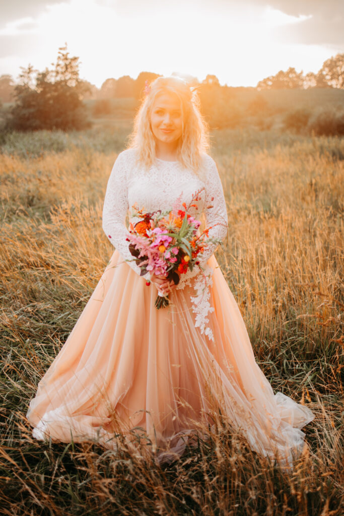 Die Braut steht im Weizenfeld bei Sonnenuntergang.
