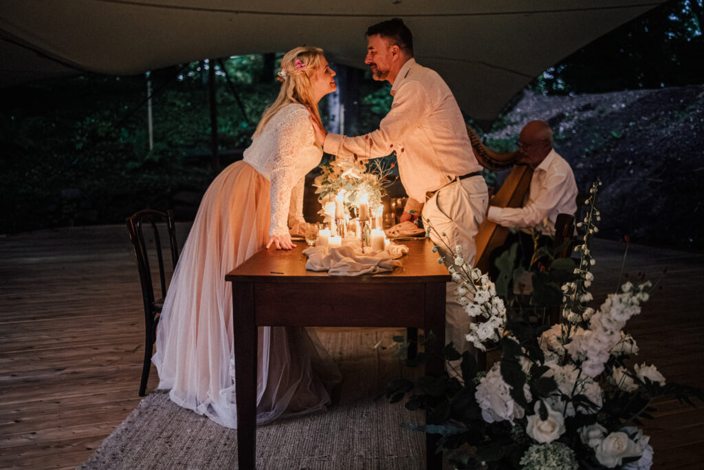 Das Paar lehnt über dem Tisch und küsst sich. 